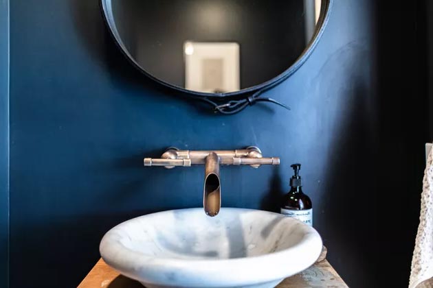 Белая раковина с современным смесителем и синей стеной в ванной